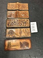 Four of the five wallets laid flat showing varied tooled designs