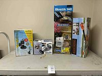 Five boxed items on table: sump pump, Shark vacuum, Bostik 260 glue gun, Wood Shield sprayer, Black & Decker leaf blower