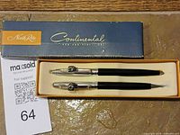 Pen and pencil set inside opened Continental box with lot card visible