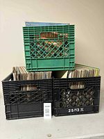 Three milk crates, two on bottom and one on top, filled with assorted records