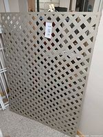 Full view of grey plastic lattice panel leaning against wall