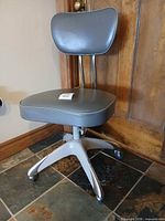 Full view of grey vinyl office chair with four-spoke caster base