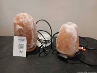 Two Himalayan salt lamps with cords on tabletop