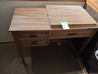 Front view of wooden sewing table with one leaf partially open and drawers visible