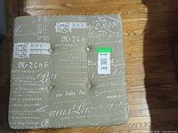 top view of square ottoman with script upholstery and tufted buttons