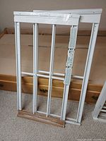 Two adjustable window guards with plastic wrap and wood-grain trim visible