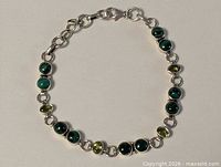 Full view of sterling silver bracelet showing alternating green stones and clasp