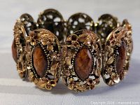 Angled close-up of bracelet showing filigree panel and cabochon detail