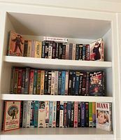 Three shelves filled with VHS tapes, showing quantity and variety