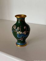 Front view of miniature green cloisonné vase with floral design