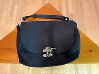 Front view showing entire black bag on wooden surface