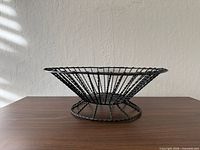 Side view of black wire basket on pedestal