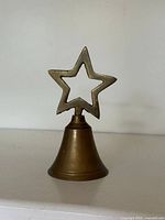 Front view of brass bell showing star finial and bell body