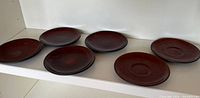 six brown stoneware plates on shelf