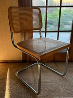 Side view of cantilever chair showing chrome base, wood frames, cane seat and backrest