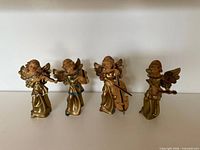 All four resin angel musician figurines standing in a row