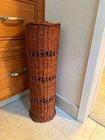 Front view of tall cylindrical wicker toilet tissue holder
