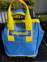 Front view of blue Playaboule carry bag with yellow handles and logo patch