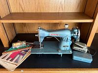 Overall lot showing sewing machine, patterns, needles, pedal and accessory tin