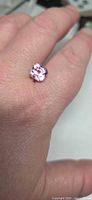 Loose bright pink cushion-cut gemstone on hand for scale