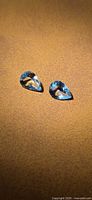 Two pear-cut blue aquamarines on brown background