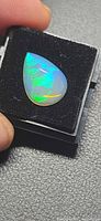 Pear cabochon opal on black foam showing play-of-color
