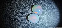 Two oval opal cabochons on black background showing body color