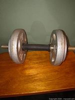 Side view of assembled adjustable dumbbell showing two grey plates on each end and black handle