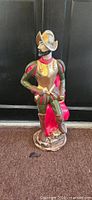 Full view of Spanish Conquistador metal statue showing armour, red cape, base