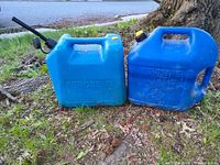 Two blue 5-gallon kerosene cans side by side outdoors, left can with spout, right can without spout