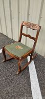Full view of carved wood rocking chair on outdoor surface