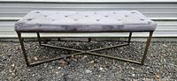 Front view of gray tufted bench showing seat and metal base