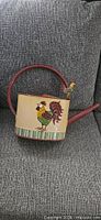 Full view of painted metal watering can on couch