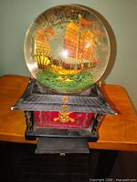Front view of light-up Pirates of the Caribbean snow globe on decorative base