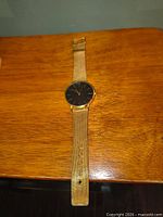 Front view of gold-tone wristwatch laid flat