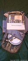 Open backpack showing plates, cutlery, cutting board, corkscrew and accessories