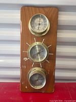 Front view of wood plaque with three brass gauges