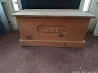 front view of unfinished pine chest with "AMY" carving