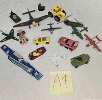 All die-cast toys laid out on surface with A4 note visible