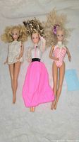All three Barbie dolls laid side by side showing full bodies and outfits