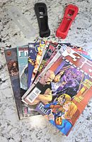 Overall view of three Wii Remote sleeves and stack of comics