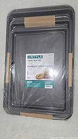 Front view of nested, shrink-wrapped Instyle cookie sheet set showing label