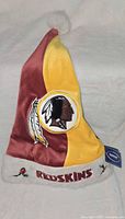 Full view of burgundy and gold Redskins Santa hat with pom-pom and brim details