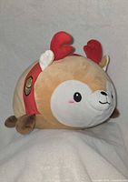 Full side view of the large tan plush with antlers and red collar