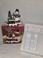 Boxed snowman water globe ornament with protective foam insert visible