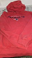 Full view of red Patriots hoodie laid flat