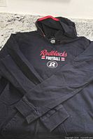 Full view of black hooded long sleeve shirt with Ottawa Redblacks graphic