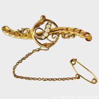 Front view showing gold scroll design and seed pearls with safety chain