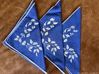 Three folded blue linen napkins showing full design and edges