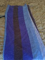 Full view of folded blue and purple striped alpaca blend throw blanket